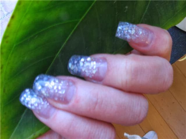 Lila glitter acryl nagels tegen een groen blad