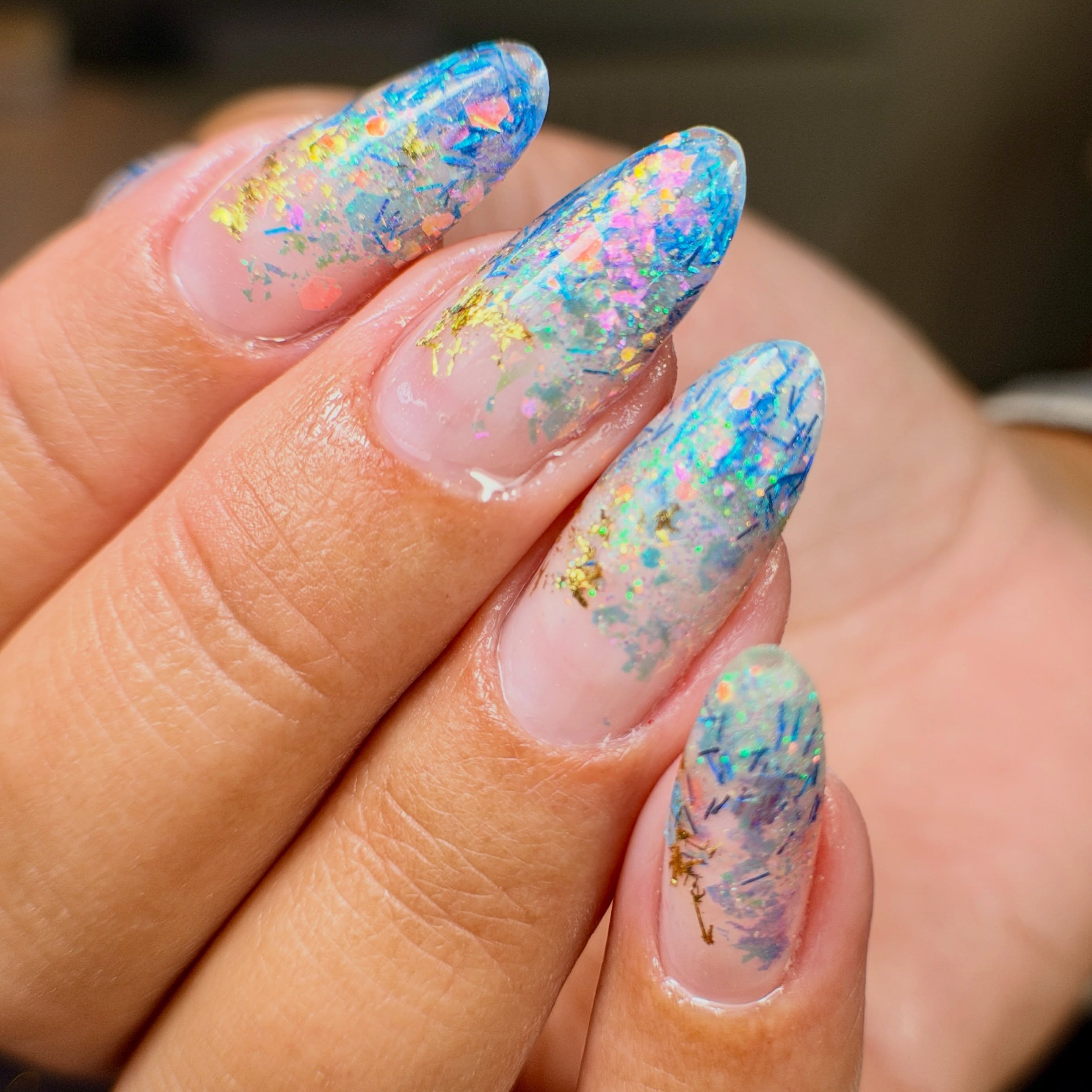 Blauwe en iriserende flakes in ombré op amandelnagels